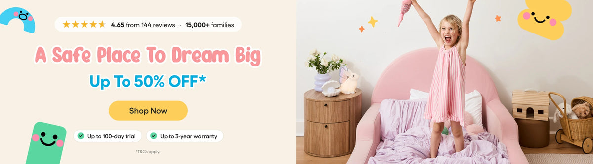 A promotional banner featuring a young girl in a pink dress standing on a pink bed with her arms raised, alongside marketing text that reads 'A Safe Place To Dream Big Up To 50% OFF*' and 'Shop Now'.